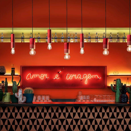 Bar mit orangem Hintergrund, roten Hängeleuchten und Neonaufschrift "amor é coragem".