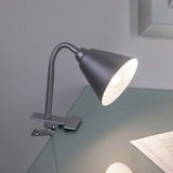 Flexible Klemmlampe Vitis in Grau mit verstellbarem Flexarm auf Glasoberfläche.