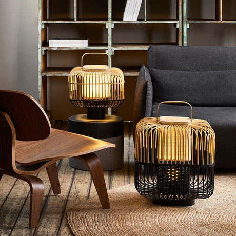 Forestier Bamboo Square Tischlampe in einem modernen Wohnambiente mit Holzstuhl und Couch.