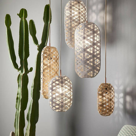 Five Forestier banana leaf pendant lights Capsule in various sizes, decorated with a houseplant.