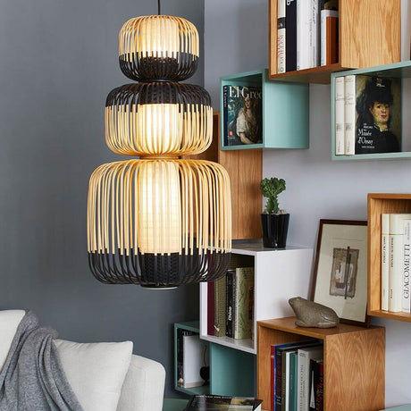 Forestier Kombi-Hängeleuchte Bamboo Totem 3-flammig in einem modernen Wohnraum mit Bücherregal.