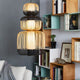 Forestier Kombi-Hängeleuchte Bamboo Totem 3-flammig in einem modernen Wohnraum mit Bücherregal.