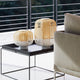 Forestier Tischlampe Bamboo Light in modernem Wohnambiente auf Tisch mit Sofa.