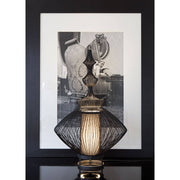 Forestier Opium table lamp with metallic wires and elegant design, in the foreground in front of a nostalgic image.