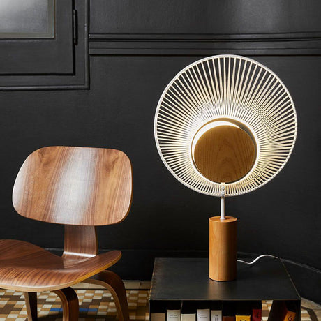 Forestier Tischlampe Oyster 65cm auf einem Tisch neben einem Holzstuhl, modernes Design mit blendfreier Beleuchtung.