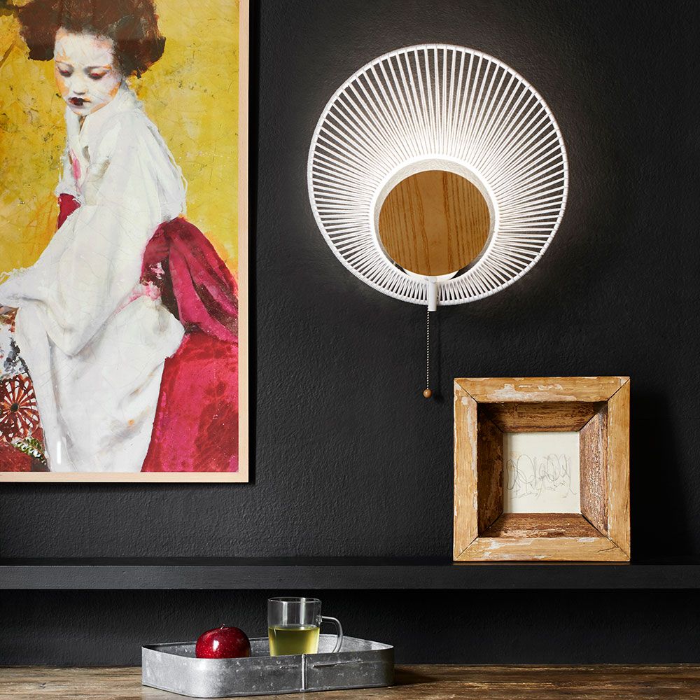 Forestier Wandleuchte Oyster mit Zugkabel an einer dunkel gestrichenen Wand, umgeben von Kunstwerken.