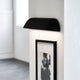 Front 36 LED utendørs vegglampe IP44 svart på en vegg, sterkt lys skinner på et bilde.