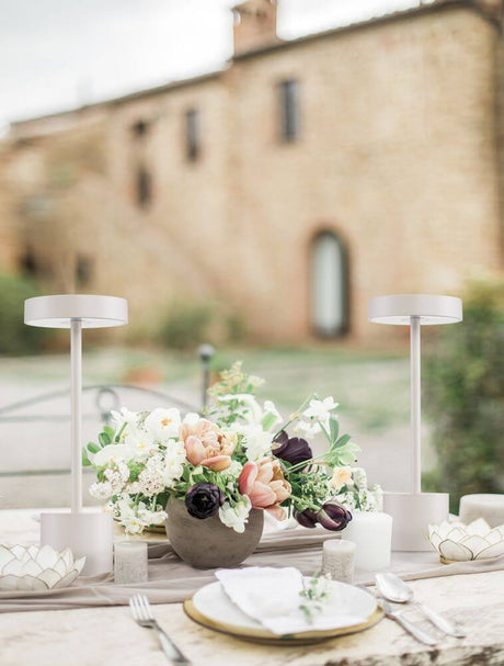 Fumo LED outdoor table lamp 3000K IP54 on a laid table with a floral arrangement.