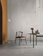 Galeo floor lamp 3000K Gold next to a modern chair and table in a stylish room.