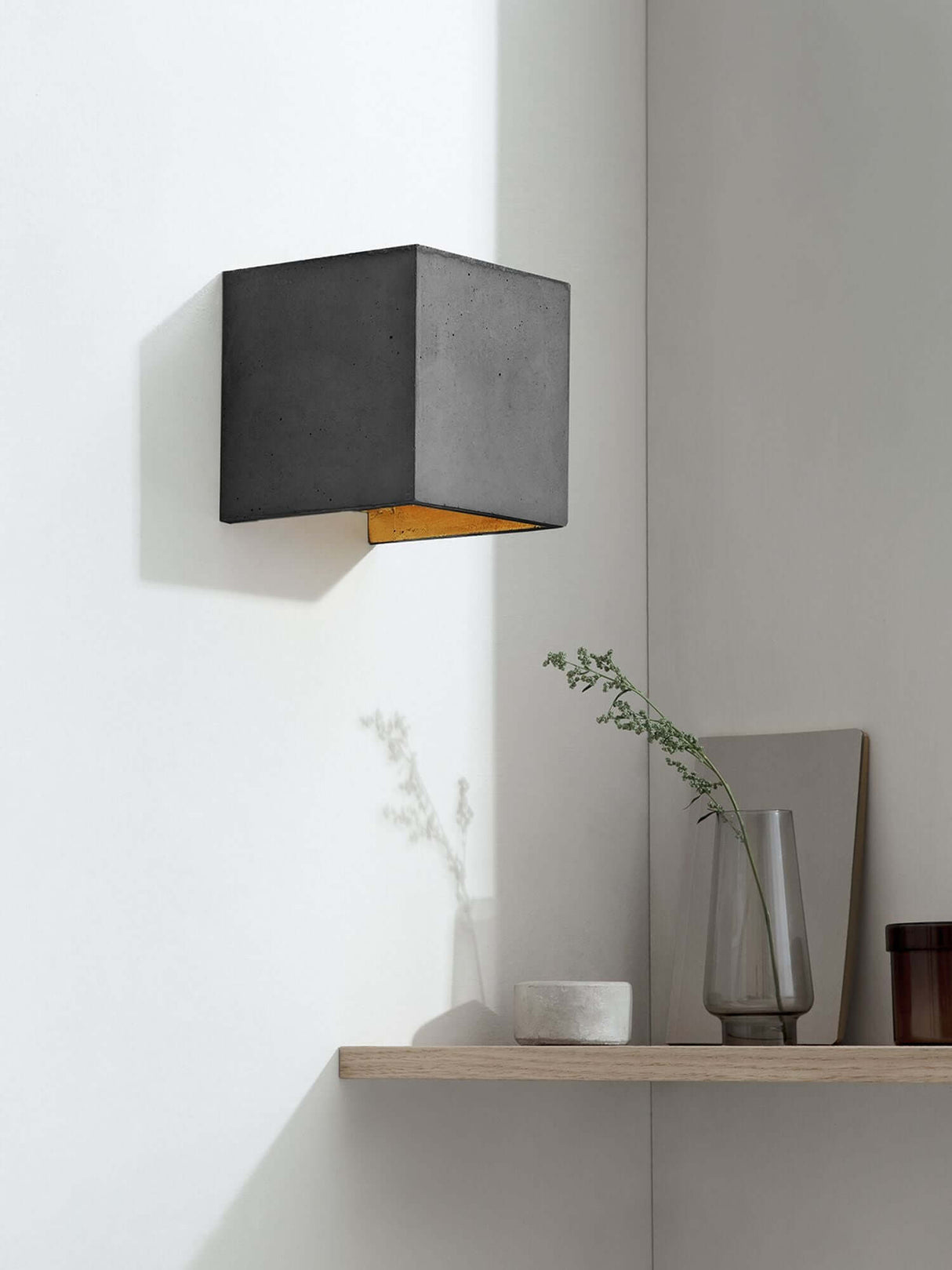 Gantlights B3 Wandlampe quadratisch Beton an weißer Wand mit goldener Innenbeschichtung und warmem Licht
