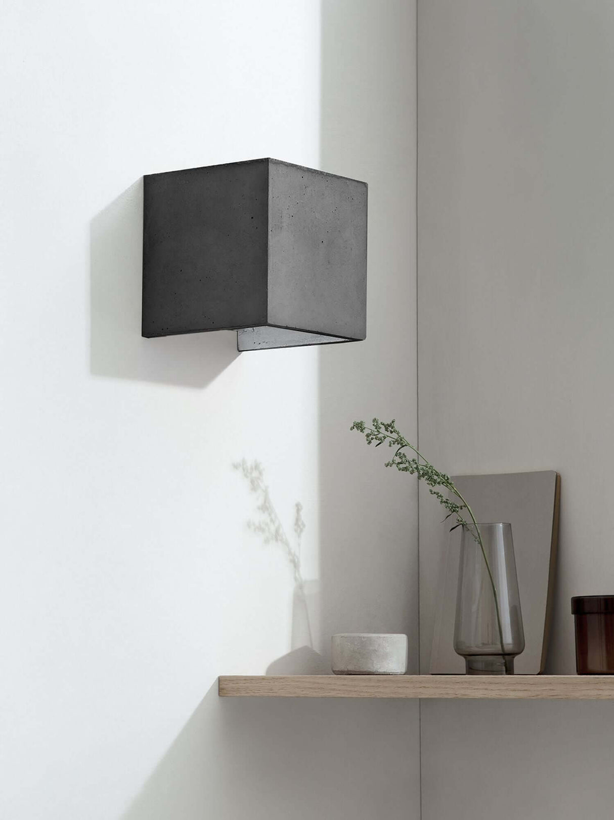 Gantlights B3 Wandlampe quadratisch Beton an heller Wand, grauer Betonwürfel mit goldener Innenfläche abstrahlt warmes Licht