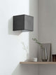Gantlights B3 Wandlampe quadratisch Beton an heller Wand, grauer Betonwürfel mit goldener Innenfläche abstrahlt warmes Licht