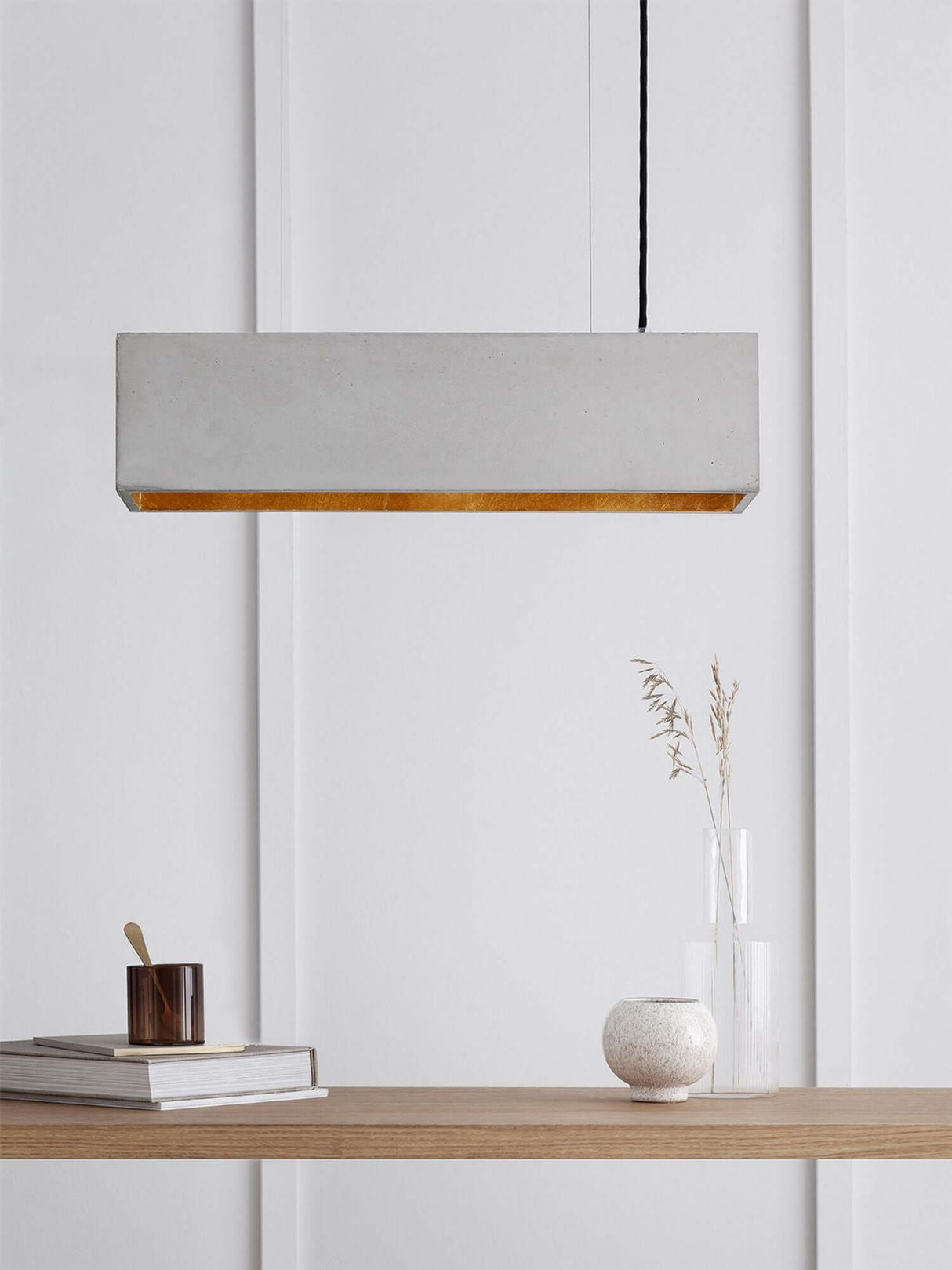 Gantlights B4 LED-Pendelleuchte Beton 56cm dimmbar über einem modernen Tisch mit Dekoration.