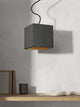 Gantlights B5 Beton Hängeleuchte in minimalistischem Design über einem Tisch mit Bücher und Becher.