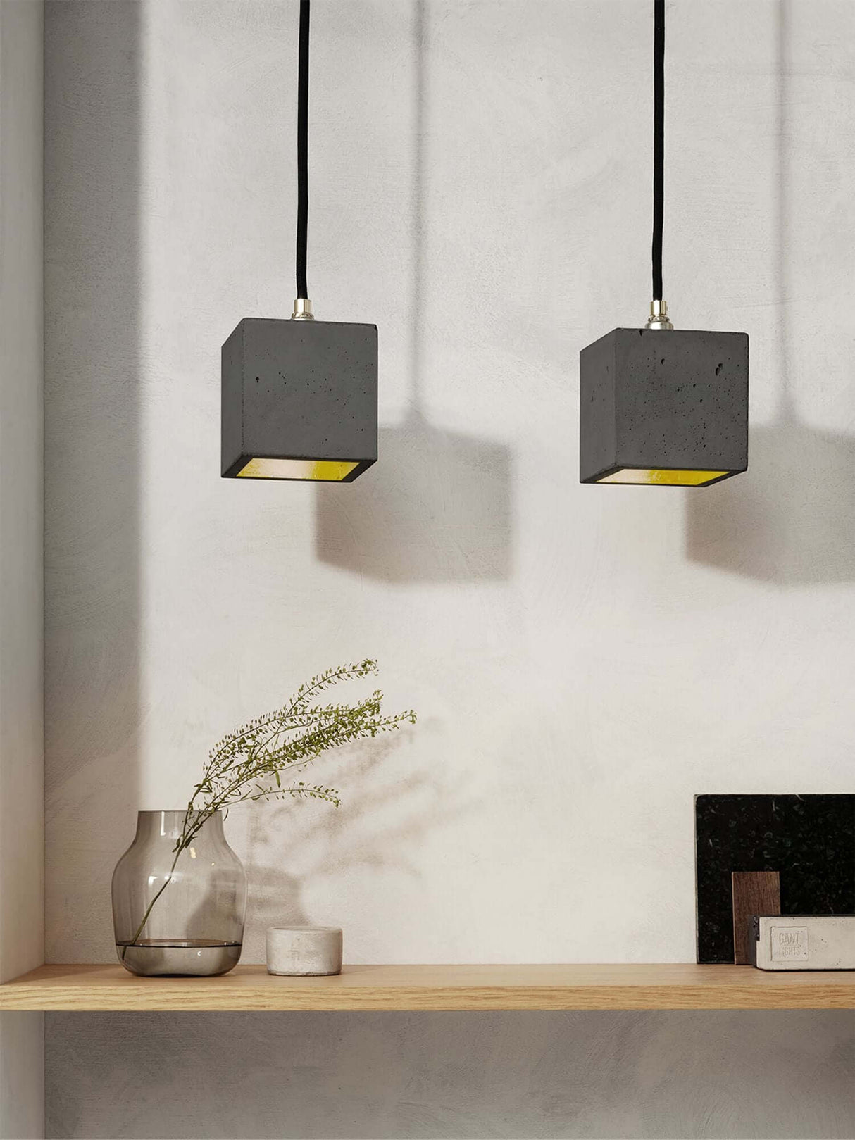Gantlights B6 Hängelampe Beton über einer Holzregal mit dekorativen Elementen