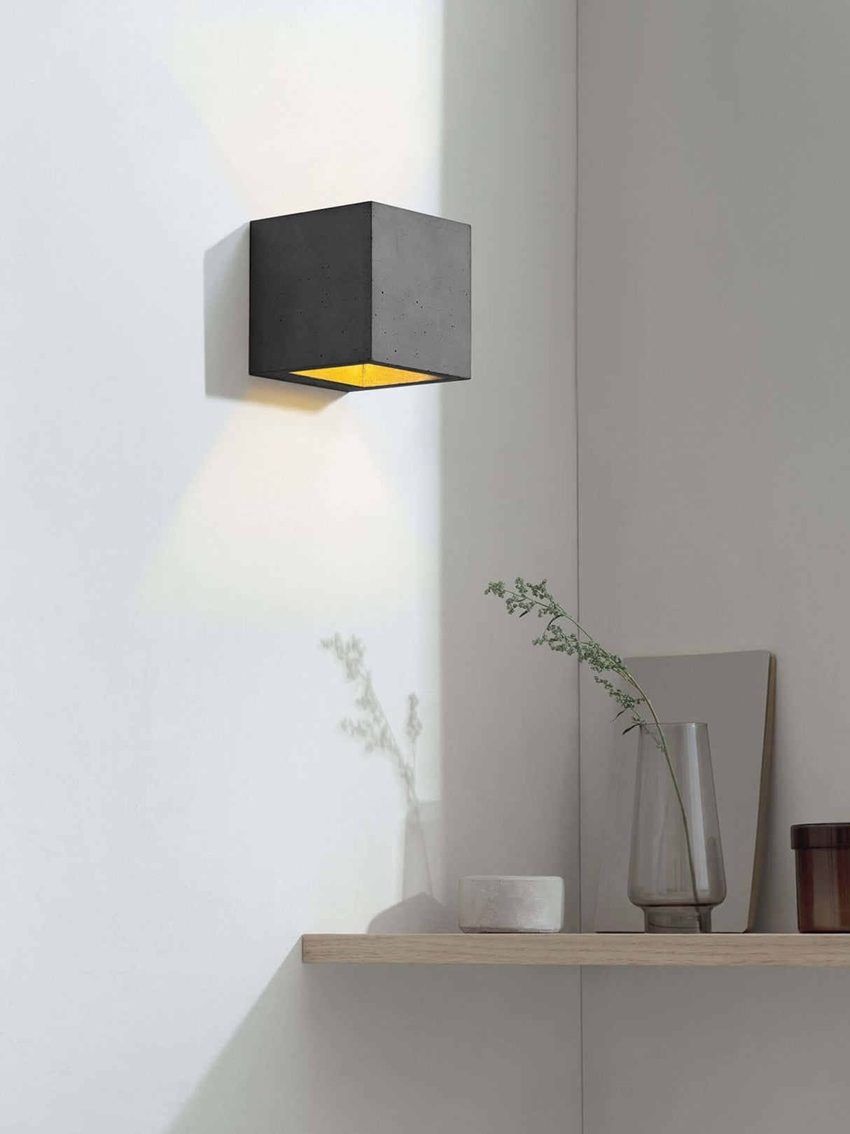 Gantlights B9 Wandleuchte Up & Down an einer Wand, strahlt warmes Licht in einem modernen Raum aus Beton.
