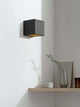 Gantlights B9 Wandleuchte Up & Down in schwarzem Beton mit goldener Innenseite an einer weißen Wand.
