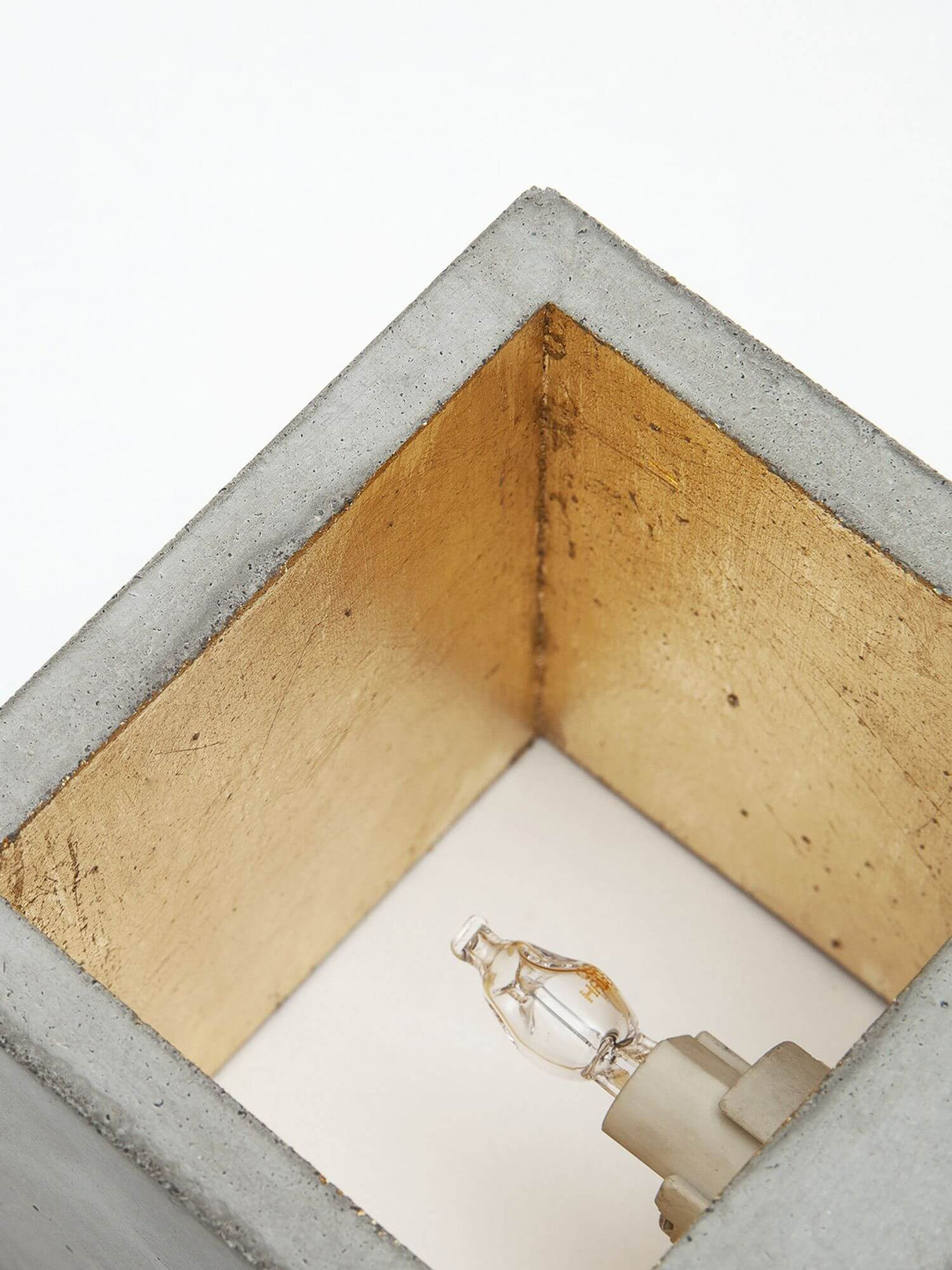 Detailansicht der Gantlights B9 Wandleuchte Up & Down aus Beton mit goldfarbenem Innenraum und G9 Fassung.