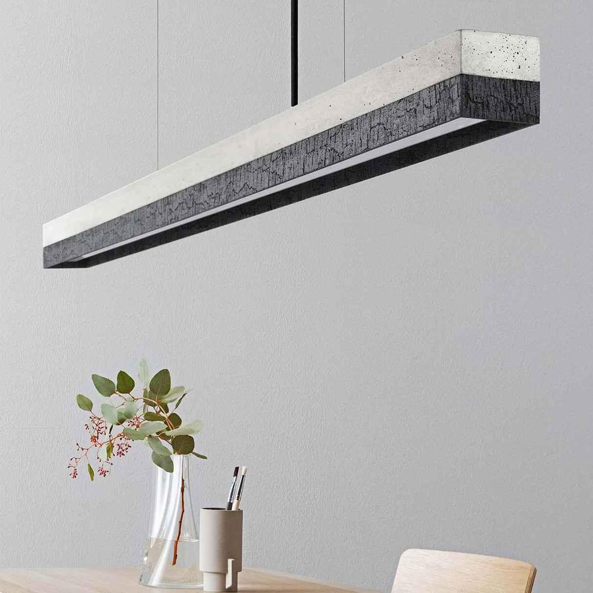Gantlights C1 LED-Pendelleuchte 122cm Beton Holz über einem Esstisch mit minimalistischer Einrichtung.