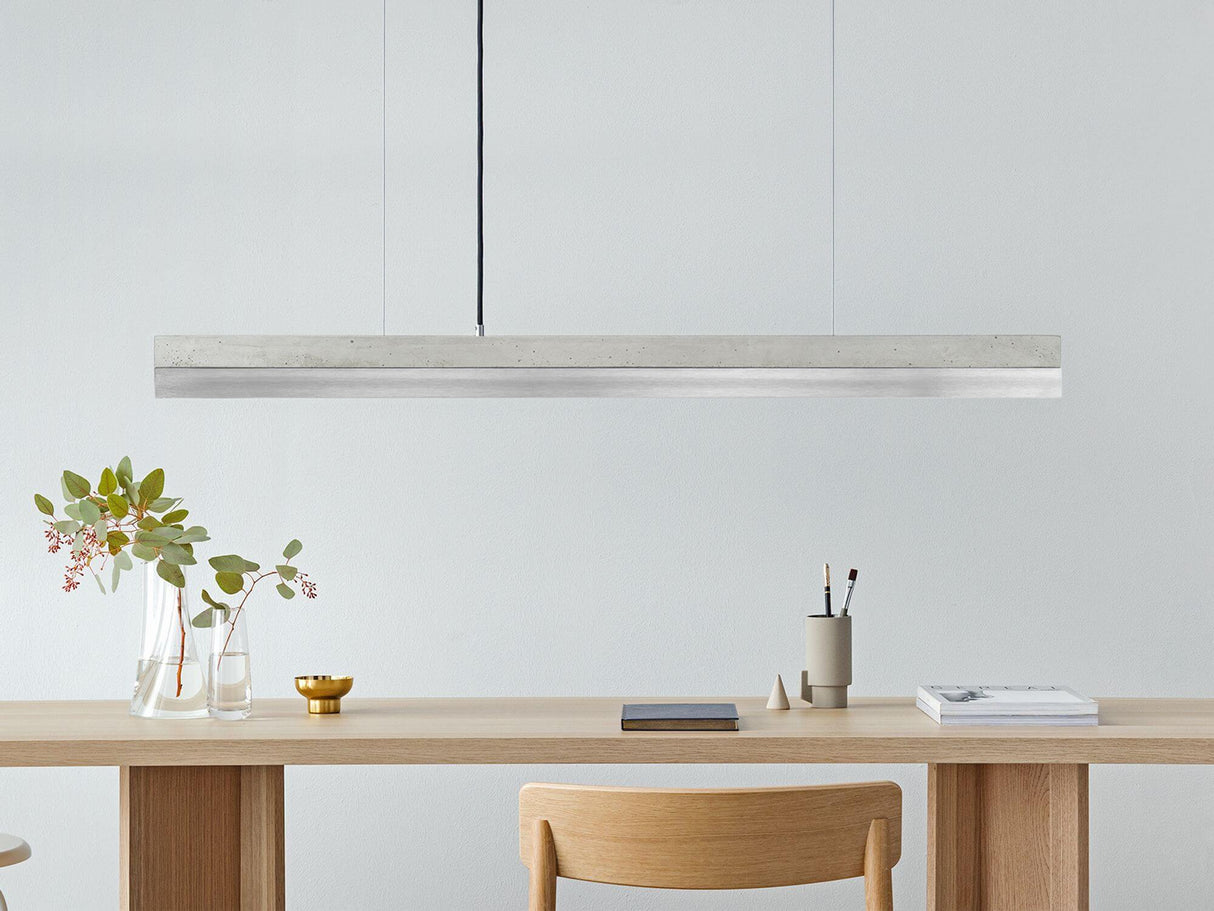 Gantlights C1 LED-Pendelleuchte 122cm Beton Holz über einem modernen Esstisch mit Pflanzen.