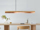 Gantlights C1 o/n LED-Hängeleuchte 122cm über einem modernen Tisch, aus Holz und Kupfer mit minimalistischer Ästhetik.