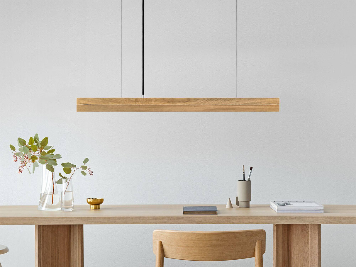 Gantlights C2 o/n LED-Pendellampe 92cm dimmbar über einem modernen Tisch mit Holzdekor.