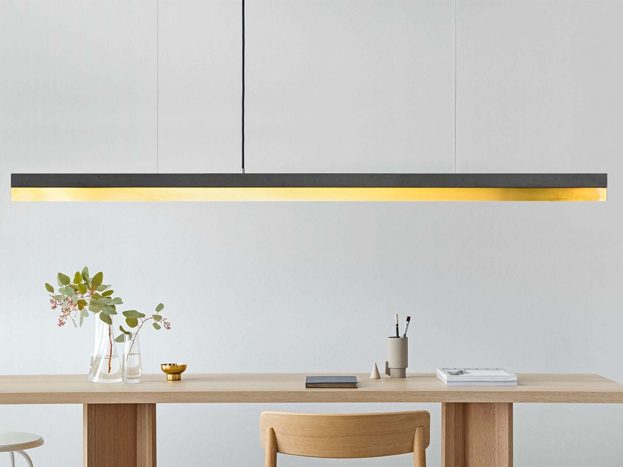 Gantlights C3 LED-Pendelleuchte dimmbar über schlichtem Holztisch, Betonkörper mit Kupfereinsatz, minimalistisches Design