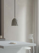 Gantlights T1 Pendelleuchte Beton hängt über einem modernen Tisch in einem minimalistischen Raum.