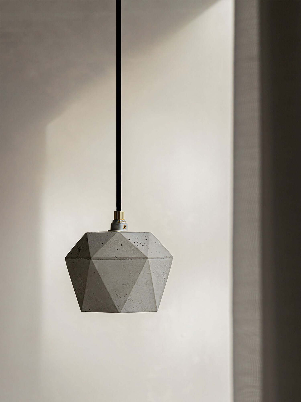 Gantlights T2 Hängelampe Beton dimmbar hängt an einem schwarzen Kabel von der Decke.