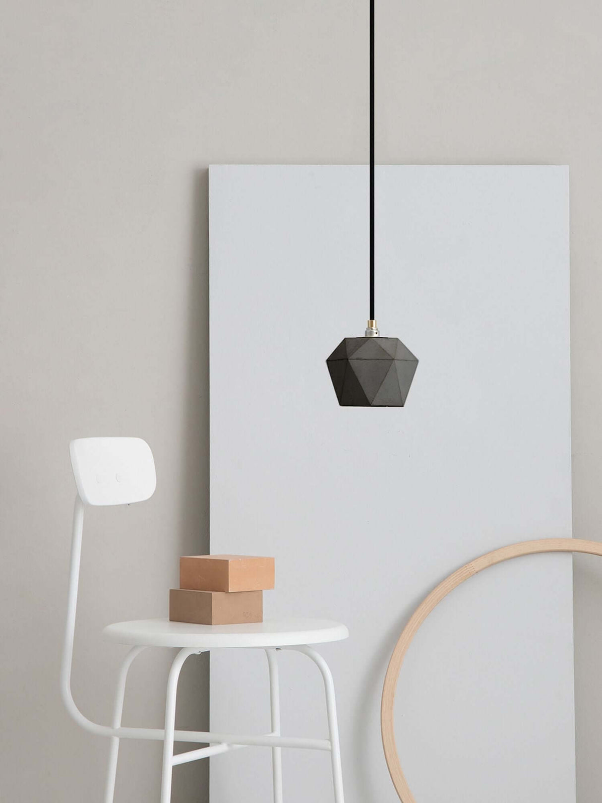 Gantlights T2 Hängelampe Beton dimmbar an einer weißen Wand über einem modernen weißen Stuhl.