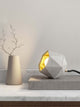 Gantlights T2-Up Tischlampe Beton auf einem Tisch mit geometrischer Form und goldener Innenseite.