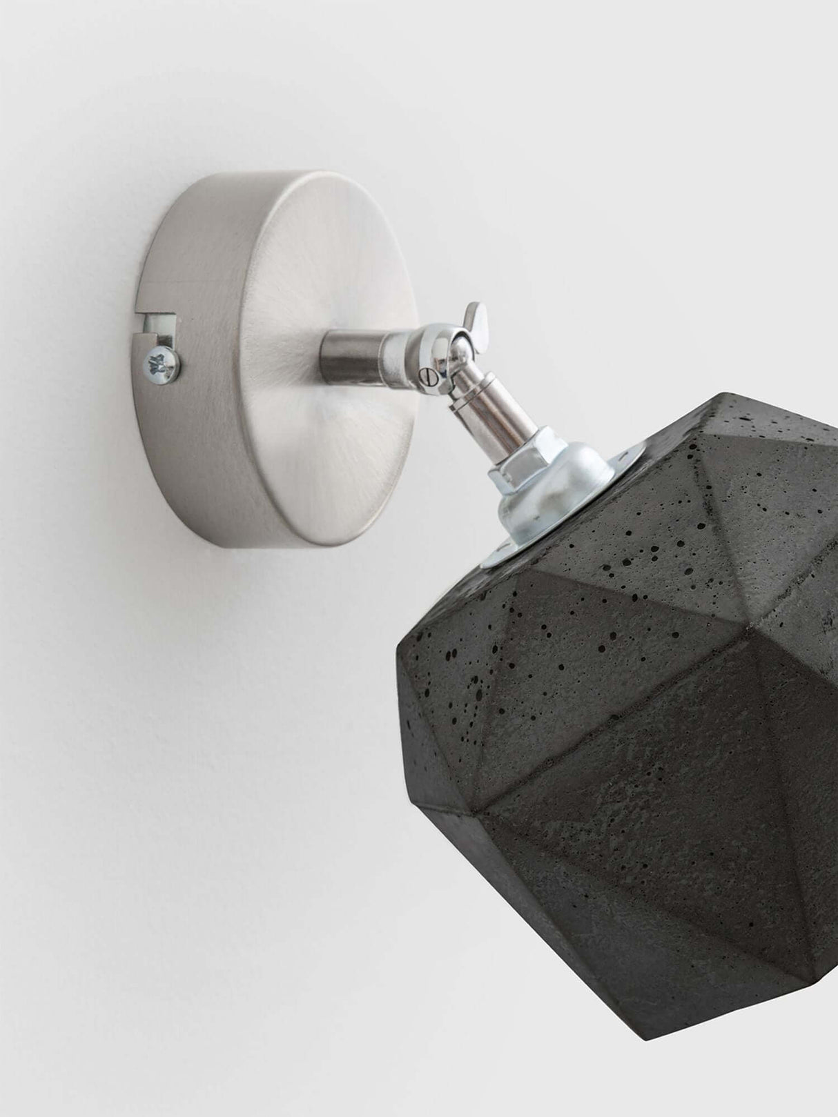 Gantlights T2 Wandspot Beton trianguliert auf einer Wand mit metallic Halterung und dreidimensionalem Betonlampe.
