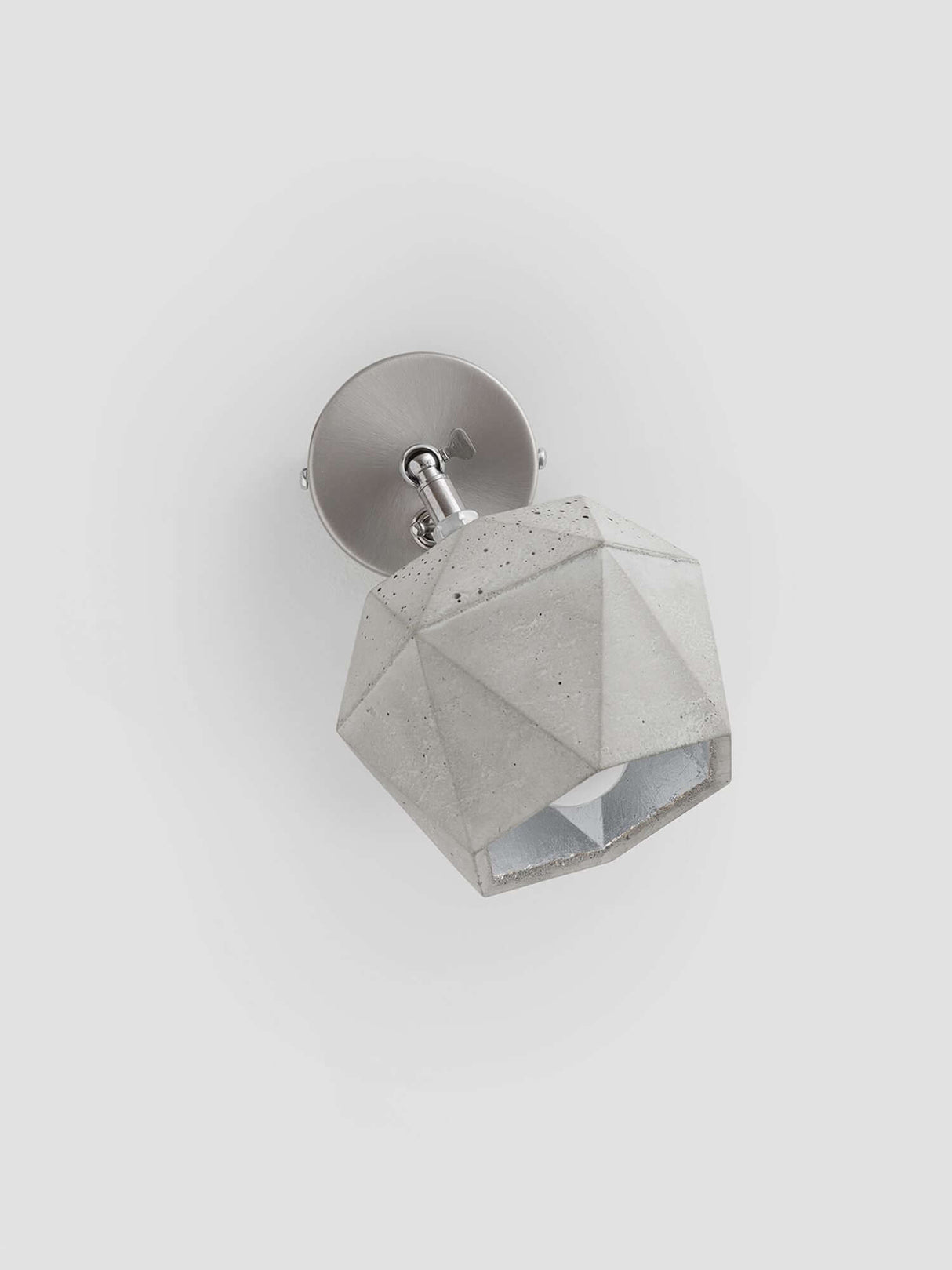 Gantlights T2 Wandspot Beton trianguliert in hellgrauem Beton mit edlen Metallakzenten.
