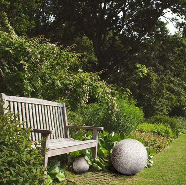 Steinoptik Gartenkugel Ø 49cm IP65 als dekorative Außenleuchte im Garten neben einer Holzbank