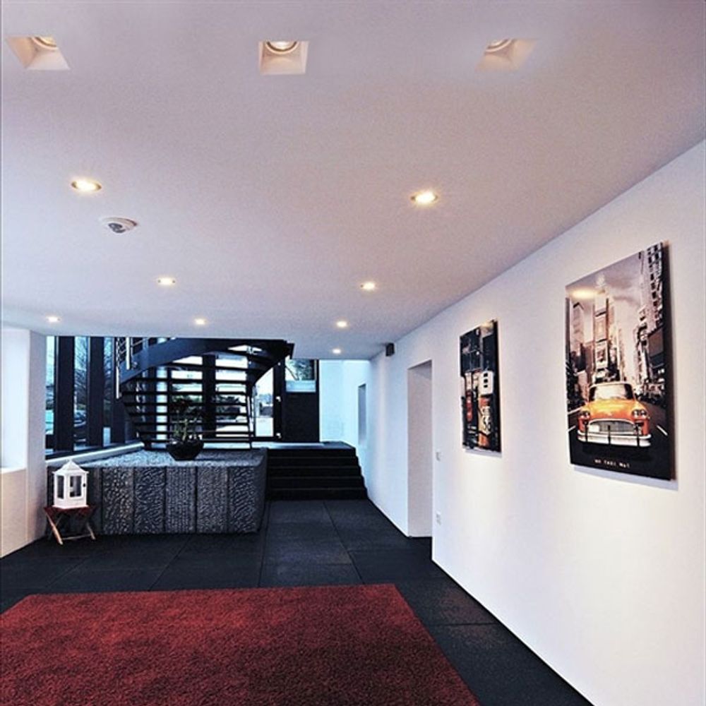 Moderne Einrichtung mit Gips-Einbaustrahler in einem hellen Raum mit Wendeltreppe und Kunstwerken an der Wand.