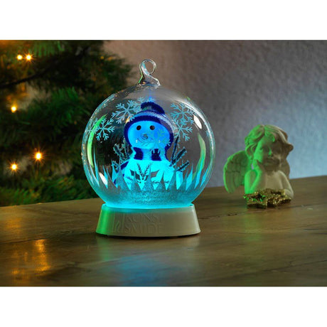 Glaskugel Schneemann mit 3 Funktionen Timer RGB-Farbwechsel 1 RGB Diode batteriebetrieben auf einem Holztisch.