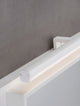 Glim LED Wandleuchte 3000K IP44 auf grauem Hintergrund, modernes Design aus schwarzem Metall und weißem Kunststoff.