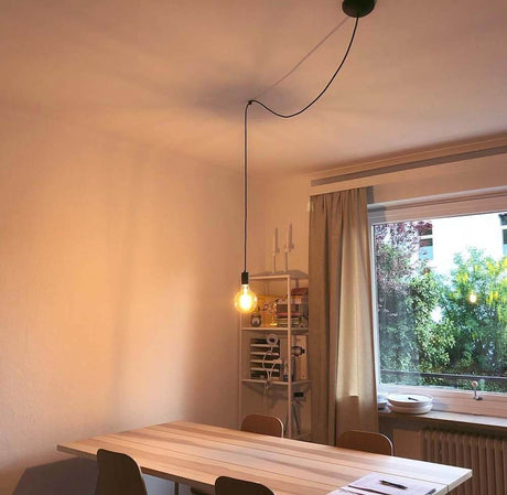 Krogafstandsophæng til Fitu pendel hvid monteret over et spisebord i en moderne stue.