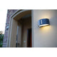 Halbrunde Außenwandlampe Bonn IP54 Anthrazit an der Außenwand eines Hauses, erzeugt bidirektionalen Lichteffekt.