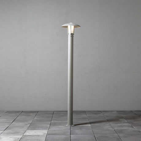 Lámpara de pie Heimdal en plata, vidrio opal en un diseño moderno sobre un fondo gris.