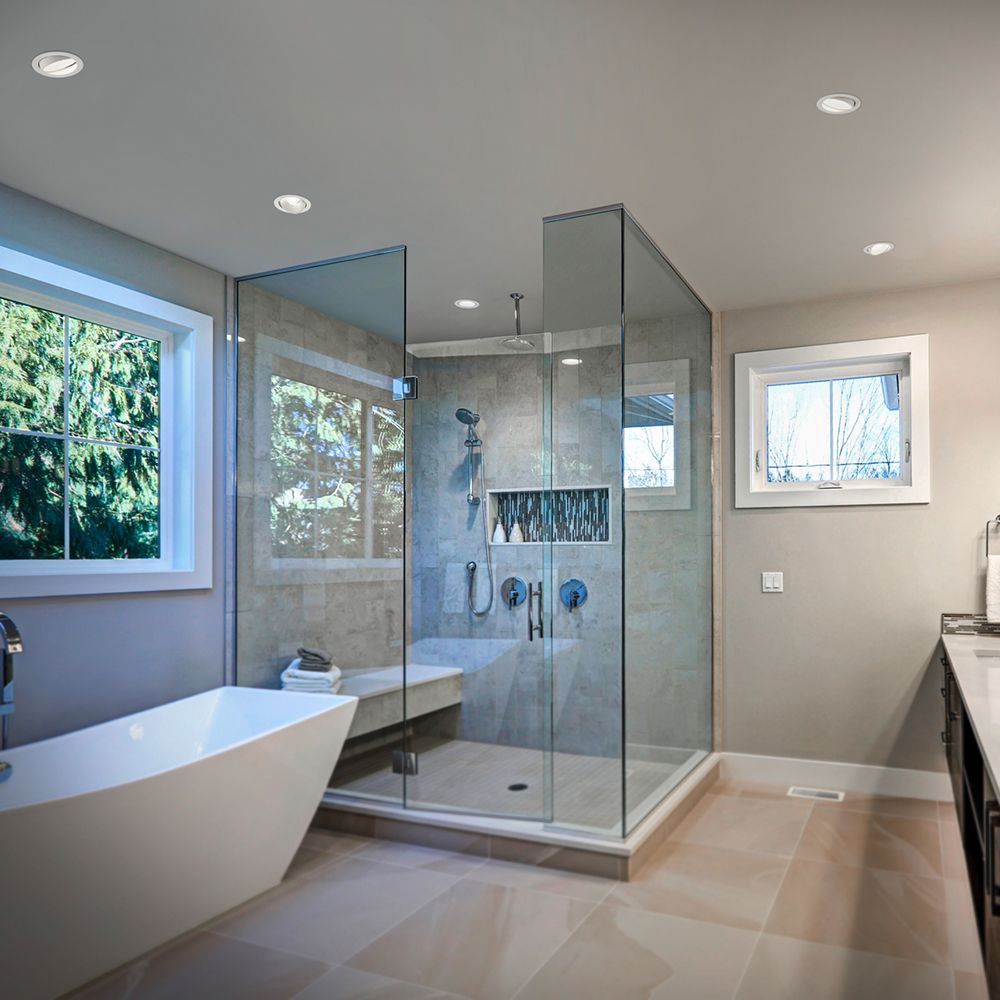 Modernes Badezimmer mit LED Decken-Einbauleuchten und Glasdusche, eleganter Badewanne und großen Fenstern.