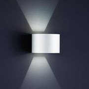 LED Siri 44 outdoor wall light - R IP54 white mounted on a grey wall, beams of light spread out.