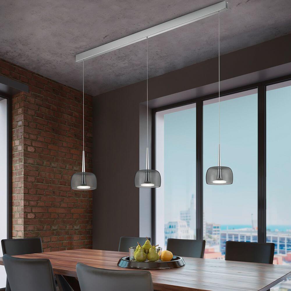 LED Pendelleuchte Flute Chrom über einem Esstisch mit transparenten und smokey grey Glasaufsätzen.