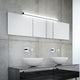 Moderne Spiegelleuchte Lado 120cm über zwei eleganten Waschbecken in stilvollem Badezimmer mit grauer Wand.