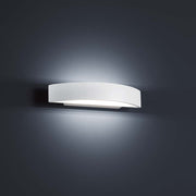 Elegant LED Yona White væglampe monteret på en væg udsender varmt lys.