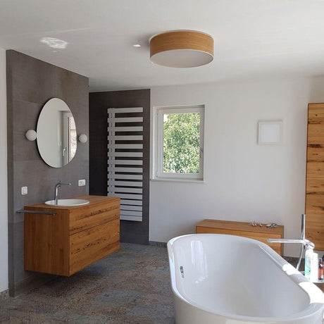 Moderne Badezimmeransicht mit Holz-Deckenleuchte Discus Deutsche Eiche und freistehender Badewanne.