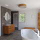 Moderne Badezimmeransicht mit Holz-Deckenleuchte Discus Deutsche Eiche und freistehender Badewanne.