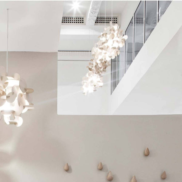 Suspension en bois Bau S 44cm dans un design d'intérieur moderne suspendue au-dessus d'un mur minimaliste.