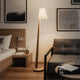Holz Stehleuchte mit geschwungenem Schirm und modernem Design in Schlafzimmer-Ambiente.