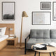 Holz Stehleuchte mit geschwungenem Schirm in modernem Wohnzimmer, kombiniert mit grauem Sofa und zeitgenössischer Kunst.